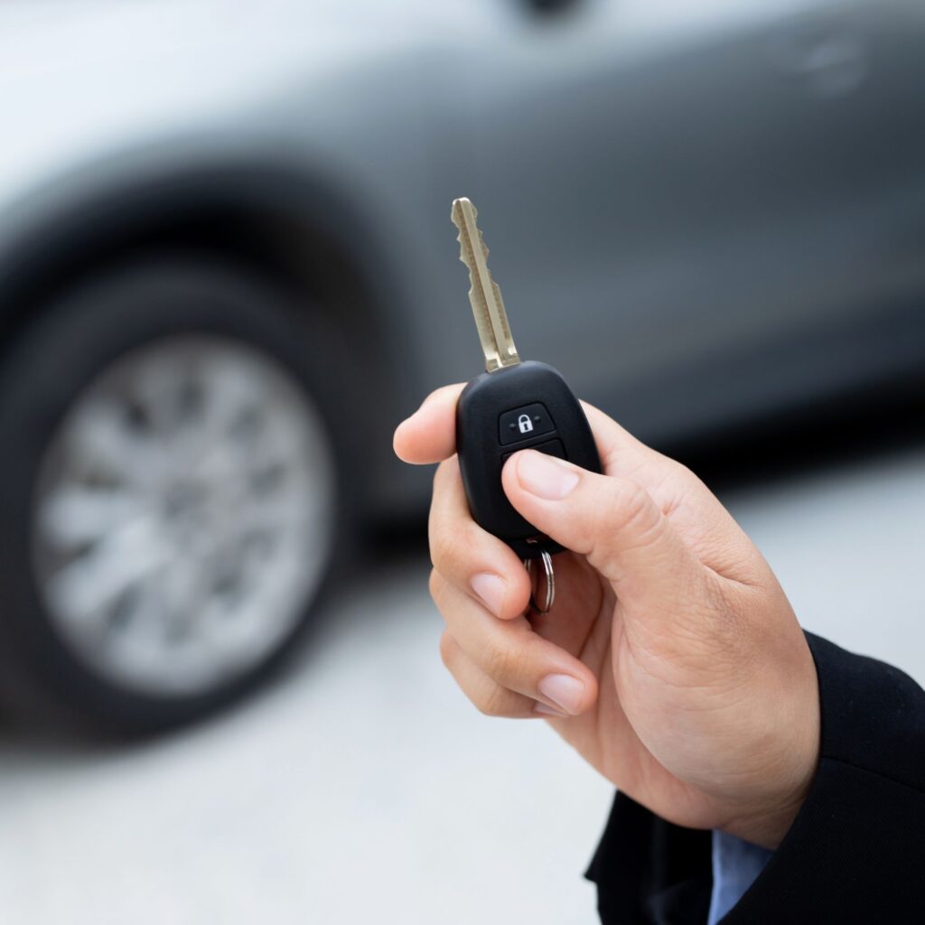 hand holding key fob with car in the background