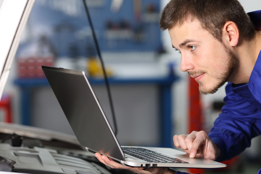 A Picture of a Mechanic Using a Computer To a Check Car.